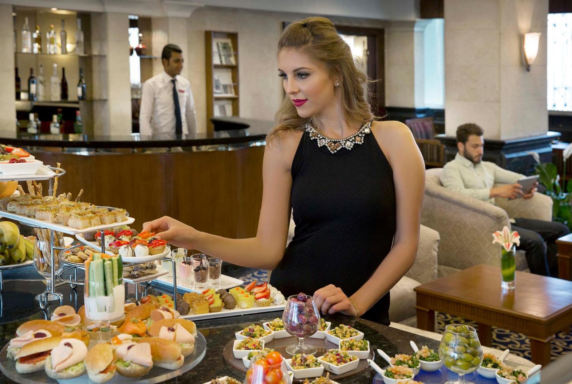 Crowne Plaza Amman By Ihg Hotel Exterior photo A woman selecting food from a buffet